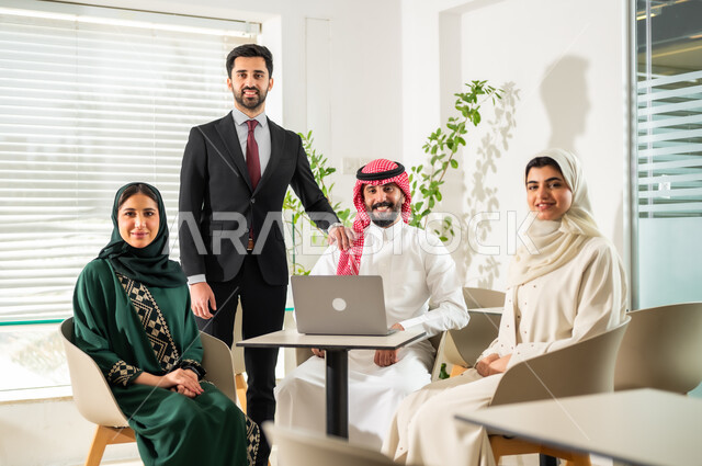 Using modern technical devices in offices, looking at the camera with gestures of happiness and pleasure to start a partnership, a business meeting between Saudi Gulf Arab employees in the meeting room, understanding and cooperation between colleagues to achieve the company’s goals, a comfortable work environment in Saudi companies.
