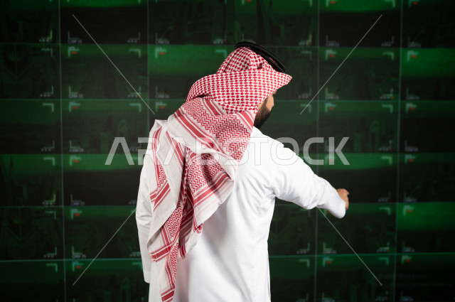 رجل سعودي خليجي يدير القسم الامني  ، يقوم بتتبع كاميرات المراقبة  ، يرتدي الزي السعودي التقليدي ، الحفاظ على الامن و الطمأنينة ، حراسة و امان 
