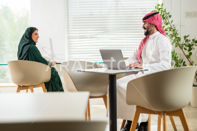 مهن ووظائف إدارية سعودية، إدارة شؤون العمل وتنظيمها، موظف عربي خليجي سعودي يرتدي الزي التقليدي يجلس أمام الحاسوب المحمول، موظفة تقوم بتدقيق أوراق العمل، دمج التقنيات الحديثة والمتطورة بالأعمال المكتبية، بيئة العمل المريحة في الشركات السعودية
