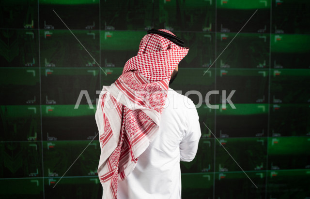 رجل سعودي خليجي يدير القسم الامني  ، يقوم بتتبع كاميرات المراقبة  ، يرتدي الزي السعودي التقليدي ، الحفاظ على الامن و الطمأنينة ، حراسة و امان 