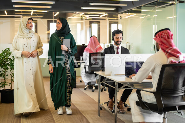 اتفاق عمل بين سيدات الاعمال، إنجاز المهام العملية عبر جهاز التابليت، استخدام الأجهزة التقنية الحديثة في المكاتب،  إمرأتان عربيتان خليجيتان محجبتان ترتديان العباءة الخليجية السعودية في مقر الشركة، مهن و وظائف مكتبية نسائية