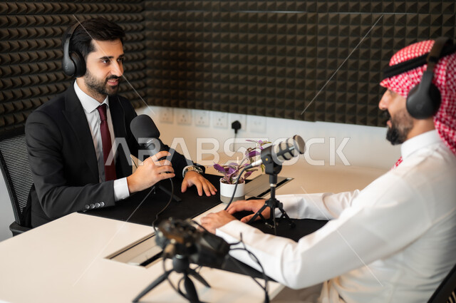 النقاشات والحوارات بين الزملاء، رجل عربي خليجي سعودي يرتدي الثوب والشماغ التقليدي مع رجل بالبدلة الرسمية في مقابلة عمل داخل مقر الشركة، ايماءات الفرح والسرور، معدات وأجهزة تسجيلات الصوت،  اجراء بث صوتي مباشر ( بودكاست ) عبر برامج التواصل الاجتماعي