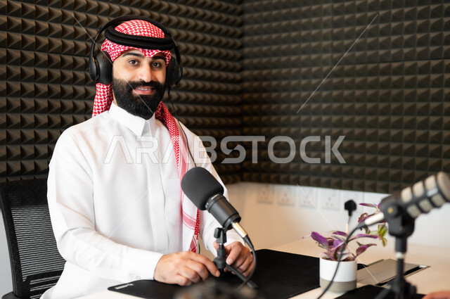 تعابير الحماس والسرور، رجل عربي خليجي سعودي مبتسم يرتدي الثوب والشماغ التقليدي في مقابلة عمل داخل مقر الشركة، معدات وأجهزة تسجيلات الصوت،  اجراء بث صوتي مباشر ( بودكاست ) عبر برامج التواصل الاجتماعي، النظر إلى الكاميرا