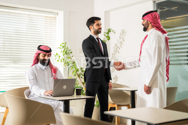 المصافحة وعقد إتفاقات وصفقات عمل جديدة، المشاركة والتعاون في إنجاز الأعمال، تطوير الخطط  وتحقيق أهداف الشركة، رجال أعمال عرب خليجيون سعوديون يقومون بإدارة شؤون العمل وتنظيمها عبر الحاسوب، مهن ووظائف إدارية مكتبية