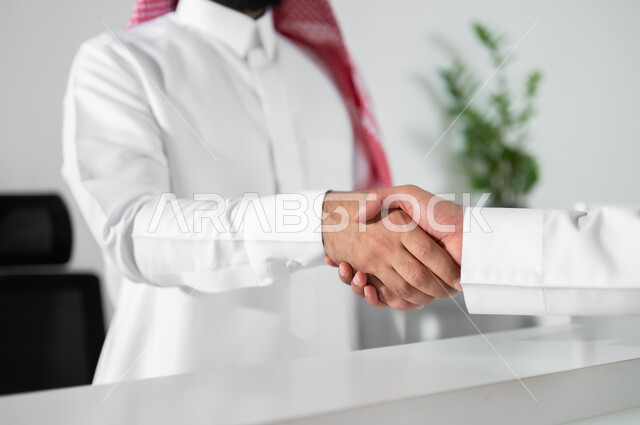 العمل في الشركات السعودية الراقية, مهن ووظائف مكتبية, التحية والسلام وإبرام اتفاقيات عمل ناجحة, صورة مقربة ليد رجل عربي خليجي سعودي يرتدي الثوب القتليدي والشماغ يقوم بالمصافحة في مقر الشركة