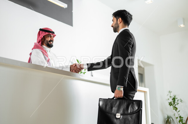 السلام والتحية بتعابير السرور, الاتفاق على المشاريع والخطط التجارية,  رجل أعمال عربي خليجي سعودي يرتدي الزي الرسمي يقوم بمصافحة الموظف في الشركة, مهن ووظائف مكتبية