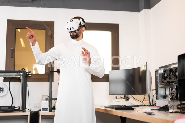 الأجهزة والتقنيات الحديثة والمتطورة، مشاهدة أفلام عبر نظارات الواقع الإفتراضي، التفاعل ومحاكاة مع العالم الخيالي، رجل عربي خليجي سعودي يرتدي الزي التقليدي يقوم بالنقر والإشارة الى شيء ما، لعب ألعاب الفيديو ثلاثية الأبعاد
