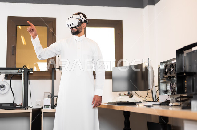 مشاهدة أفلام عبر نظارات الواقع الإفتراضي، التفاعل ومحاكاة مع العالم الخيالي، رجل عربي خليجي سعودي يرتدي الزي التقليدي يقوم بالنقر والإشارة الى شيء ما، الأجهزة والتقنيات الحديثة والمتطورة، لعب ألعاب الفيديو ثلاثية الأبعاد
