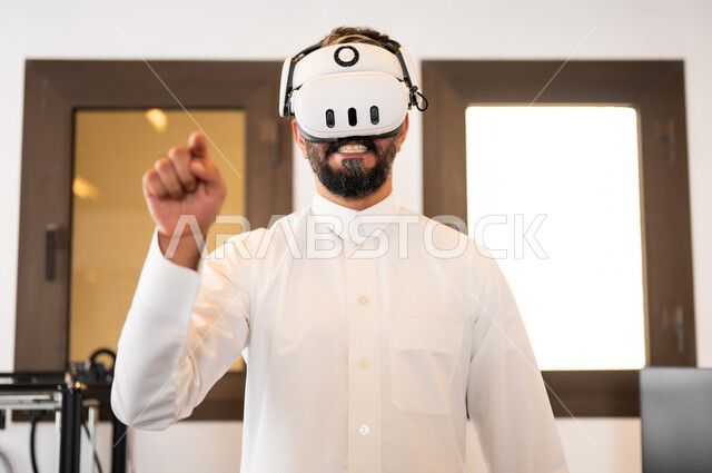 التفاعل ومحاكاة العالم الخيالي، صورة مقربة لرجل عربي خليجي سعودي يرتدي الزي التقليدي يقوم بالنقر والإشارة الى شيء ما، مشاهدة أفلام عبر نظارات الواقع الإفتراضي، الأجهزة والتقنيات الحديثة والمتطورة، لعب ألعاب الفيديو ثلاثية الأبعاد