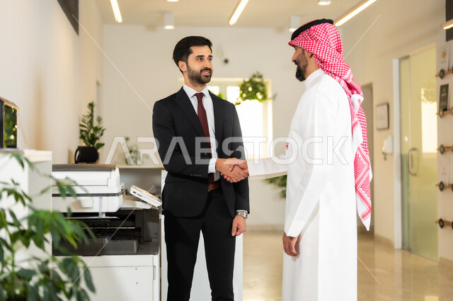 مهن ووظائف سعودية, العمل في الشركات الخليجية الراقية, التحية والسلام والاتفاق على صفقات عمل ناجحة, رجلا أعمال عربيان خليجيان سعوديان يقومان بالمصافحة بتعابير السرور