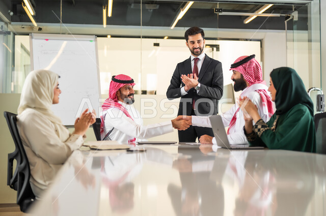 الوحدة والتفاعل الجماعي لتحقيق أهداف الشركة وحل المشكلات، المصافحة وعقد إتفاقات وصفقات عمل جديدة، تحليل المشاريع الجديدة ودراستها، استعمال السبورة لتوضيح العمليات والاجراءات المتبعة في الشركة، فريق عربي خليجي سعودي في اجتماع داخل المكتب