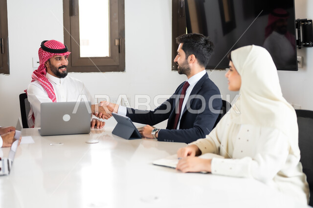 استخدام الأجهزة التقنية الحديثة في المكاتب، التفاهم والتعاون بين الزملاء لتحقيق أهداف الشركة, ايماءات السعادة والسرور لبدء الشراكة، اجتماع عمل مع موظفين عرب خليجيين سعوديين في غرفة الاجتماعات، بيئة العمل المريحة في الشركات السعودية, نقاشات خاصة بالعمل,