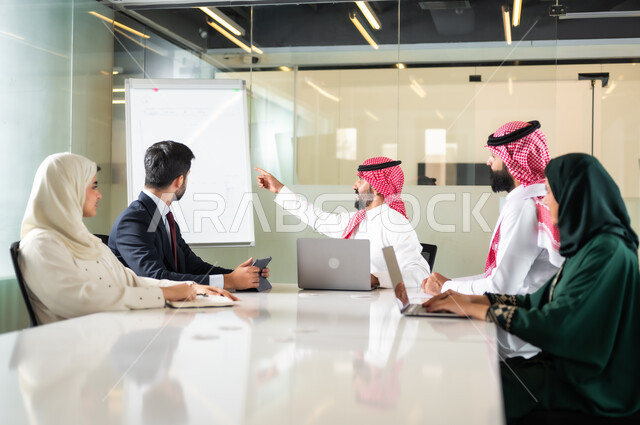 التعاون بين الزملاء لتحقيق أهداف الشركة، بيئة العمل المريحة في الشركات السعودية، استخدام الأجهزة التقنية الحديثة في المكاتب، استعمال السبورة لتوضيح الأفكار، اجتماع عمل بين موظفين عرب خليجيين سعوديين في غرفة الاجتماعات