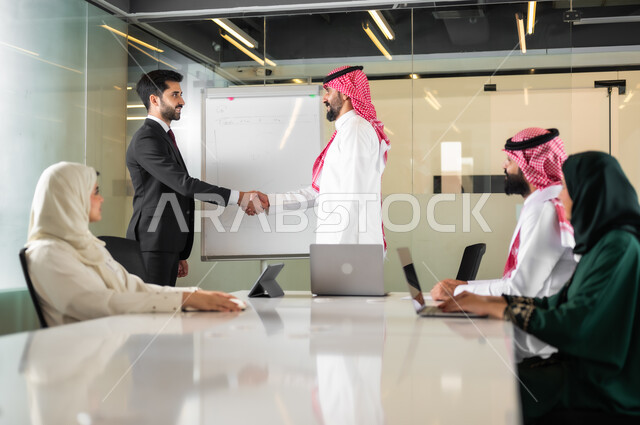 Unity and group interaction to achieve the company’s goals and solve problems, shaking hands and concluding new business agreements and deals, analyzing and studying new projects, using the blackboard to clarify the processes and procedures followed in the company, a Saudi-Gulf Arab team in a meeting inside the office