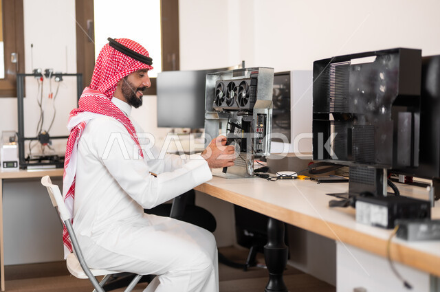 الإستعداد لإجراء (بودكاست) عبر مواقع التواصل الاجتماعي في الاستوديو، التحضير لعمل البث المباشر و تشغيل الاجهزه الالكترونيه, شاب عربي خليجي سعودي يرتدي الزي التقليدي والشماغ يقوم بربط الأسلاك بجهاز الحاسوب
