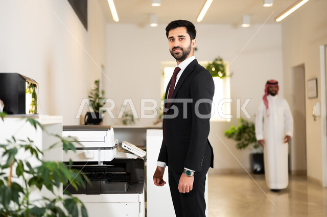 The concept of elegance and attention to external appearance, a smiling Saudi Arabian Gulf businessman wearing a formal uniform looking at the camera confidently, youthful professions and jobs, working in high-end Gulf companies
