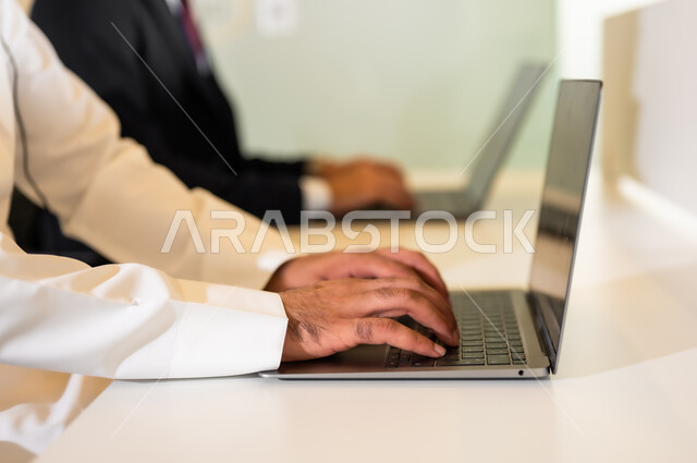 استخدام الأجهزة والتقنيات الحديثة, صورة مقربة لايدي رجلان عربيان خليجيان يعملان في خدمة العملاء, الإجابات على الأسئلة و الاستفسارات, عقد إجتماع عبر الانترنيت, متابعة وتطوير الأعمال من خلال أجهزة الحاسوب