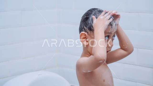 الشعور بالاسترخاء والراحة، تنظيف فروة الرأس وحمايتها من القشرة، مفهوم الاستحمام بالمياه الدافئة، العناية والاهتمام بالنظافة الشخصية، صورة مقربة لولد عربي خليجي سعودي يقوم بغسل شعره بالماء والصابون داخل الحمام