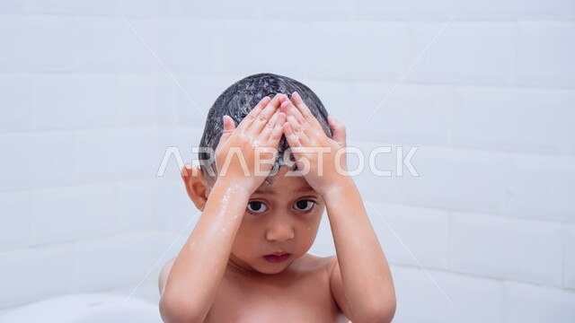 تنظيف فروة الرأس وحمايتها من القشرة، مفهوم الاستحمام بالمياه الدافئة، العناية والاهتمام بالنظافة الشخصية، صورة مقربة لولد عربي خليجي سعودي يقوم بغسل شعره بالماء والصابون داخل الحمام، الشعور بالاسترخاء والراحة