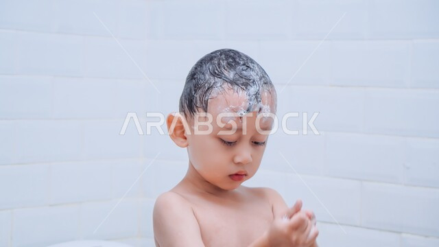 الاستحمام بالمياه الدافئة، العناية والاهتمام بالنظافة الشخصية، صورة مقربة لولد عربي خليجي سعودي يقوم بغسل شعره بالماء والصابون داخل الحمام، تنظيف فروة الرأس وحمايتها من القشرة، الشعور بالاسترخاء والراحة