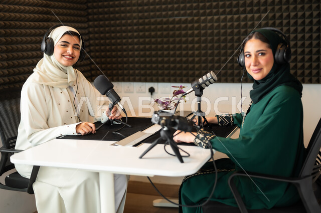 العمل في مجال الإذاعة الصوتية, تعابير الحماس والسرور, إستخدام اجهزه تقنيه حديثه, سيدتان عربيتان سعوديتان خليجيتان محجبتان مبتسمتان ترديان العباءة وسماعة الرأس, حوارات ونقاشات استعلامات واستفسارات، النظر الى الكاميرا بايماءات السعادة