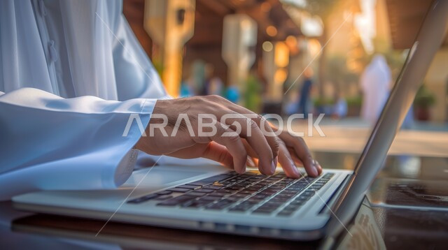 Completing required work tasks, integrating work with techniques and technology, the concept of managing and organizing business affairs through technical devices, office administrative professions and jobs, a close-up picture of the hands of a Saudi Arabian Gulf businessman working on a laptop inside the office