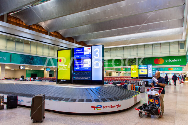Providing services and facilities to visitors, baggage claim at Dubai International Airport, the concept of tourism and travel in the United Arab Emirates, electronic information boards, means of transportation and air transportation.
