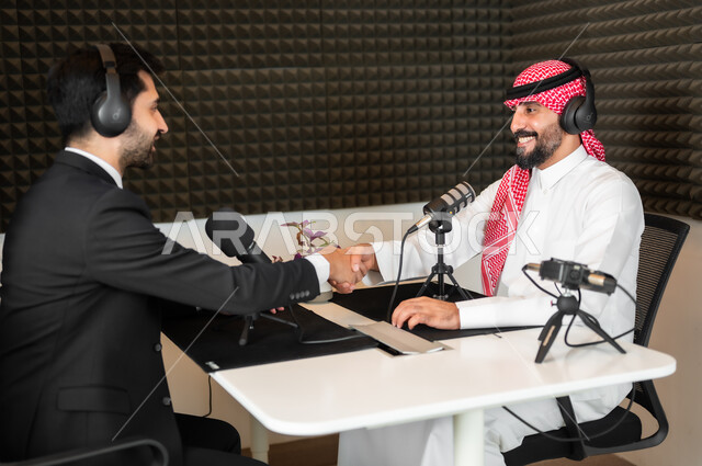 اجراء بث صوتي مباشر (بودكاست) عبر برامج التواصل الاجتماعي، معدات وأجهزة تسجيلات الصوت، رجل عربي سعودي خليجي يرتدي الثوب والشماغ التقليدي مع رجل بالبدلة الرسمية  يقومان بمصافحة بعضهما، القاء التحية والترحيب، تعابير الفرح والسعادة