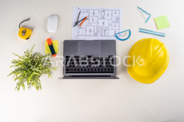  تصوير مقرب من الأعلى , لمهندس معماري خليجي , مهندس يعمل على تصميم العمارات من خلال اللابتوب على مكتب أبيض , وظيفه ومهن , بيئة عمل , خلفية بيضاء .