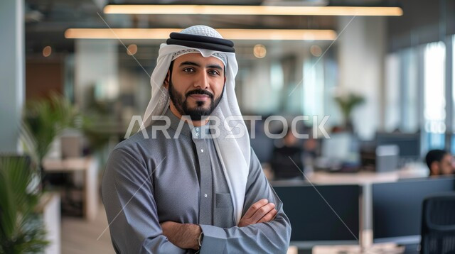 الاهتمام بالمظهر الخارجي والأناقة، مفهوم الرجولة والثقة بالنفس ، الوقوف باستقامة والنظر الى الكاميرا، صورة مقربة لرجل عربي خليجي سعودي مبتسم يرتدي الزي التقليدي والغترة مكتف الأيدي