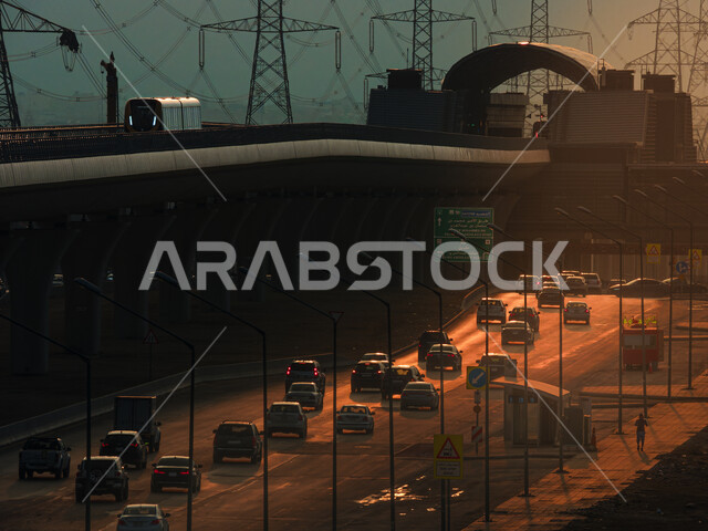 الجسر المعلق المدعوم بالكوابل في وقت غروب الشمس، قطار خط مترو مدينة الرياض في المملكة العربية السعودية، وسائل النقل والمواصلات السريعة، التصميم الهندسي المعماري للطرق والشوارع بالعاصمة، حركة المرور وسير السيارات في الشوراع الرئيسية