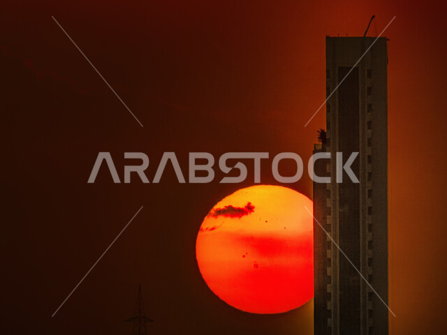 The view of the blazing sun disk in the sky, urban development in the city of Riyadh, towers and skyscrapers at sunset, architectural art in the Kingdom of Saudi Arabia