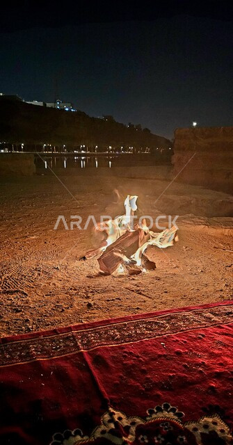 رحلة وكشتة برية في المناطق الصحراوية، الاستمتاع في الأجواء والجلسات الليلية الهادئة ، قضاء العطلة في براري المملكة العربية السعودية، شعلة من النار وسط الصحراء في وادي نمار وقت الليل