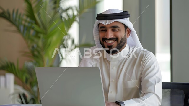 دمج العمل مع التقنيات والتكنولوجيا، مفهوم إدارة شؤون الأعمال وتنظيمها عبر الاجهزة التقنية، مهن ووظائف ادارية مكتبية, رجل اعمال عربي خليجي سعودي يعمل على الحاسوب المحمول داخل المكتب، إنجاز المهام العمل المطلوبة