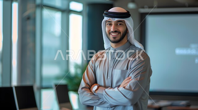 مفهوم الأناقة والإهتمام بالمظهر الخارجي، رجل أعمال عربي خليجي سعودي مبتسم يرتدي الزي التقليدي ينظر الى الكاميرا يقف باستقامة وايدي متقاطعة، مهن ووظائف ادارية سعودية، توضيح مهام العمل واستراتيجيات الشركة
