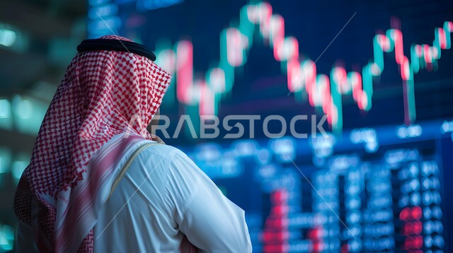 خلفية هولوجرامية ثلاثية الأبعاد، متابعة الرسوم البيانيه على الشاشات الالكترونيه المضيئه، رجل أعمال عربي خليجي سعودي يقوم بمراقبة ارتفاع وانخفاض الأسهم في سوق البورصه، دمج التكنولوجيا المتطورة مع العمل, تداول العملة الرقمية،  رؤية مستقبليه 2030