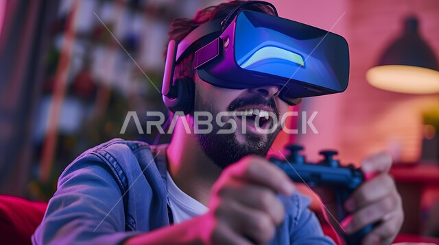 Technological devices and modern techniques, feeling fun and amusement by simulating the imaginary world, a close-up image of a young Arab Gulf Saudi man wearing 3D virtual reality (VR) glasses and holding a joystick in his hand playing entertainment video games
