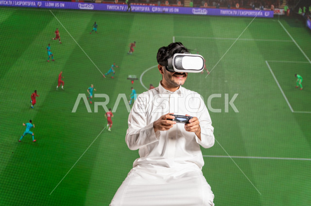 خاصية الهولوجرام ، رجل سعودي خليجي يقضي وقت ترفيهي  ،يضع جهازVR Box،  استخدام تقنية الهولوجرام ثلاثية الابعاد ، صور تجسيمية خاصة بمباريات كرة القدم ، صور متحركة بأبعاد مختلفة ، تصوير ثلاثي الابعاد للأجسام