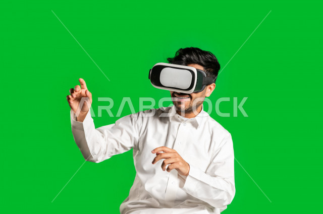 Chroma, a happy Saudi Gulf man, puts the VR Box, face and hand gestures indicating happiness and enjoyment, the use of 3D technology, green background