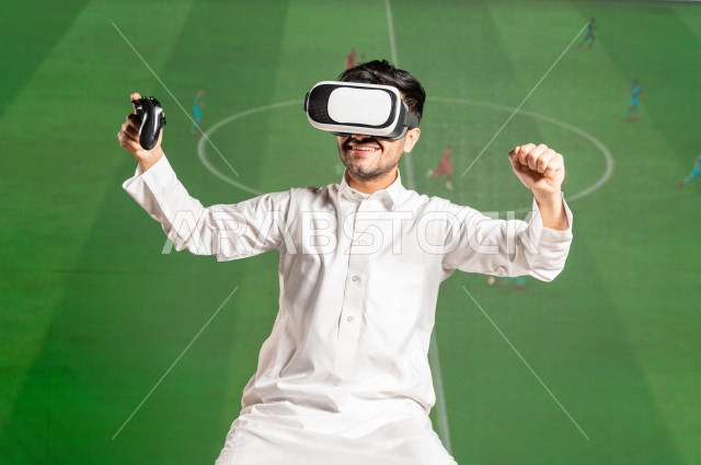 خاصية الهولوجرام ، رجل سعودي خليجي يقضي وقت ترفيهي  ،يضع جهازVR Box،  استخدام تقنية الهولوجرام ثلاثية الابعاد ، صور تجسيمية خاصة بمباريات كرة القدم ، صور متحركة بأبعاد مختلفة ، تصوير ثلاثي الابعاد للأجسام