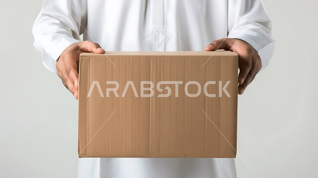 الشحن والتوصيل ذات الجودة العالية، بورتريه مقرب لايدي شاب عربي خليجي سعودي يرتدي الزي التقليدي يعمل كمندوب مبيعات ويحمل بيده صندوق كرتوني، التسوق وطلب المنتجات عبر الإنترنت, عملية توصيل الطلبات للزبائن، خلفية بيضاء
