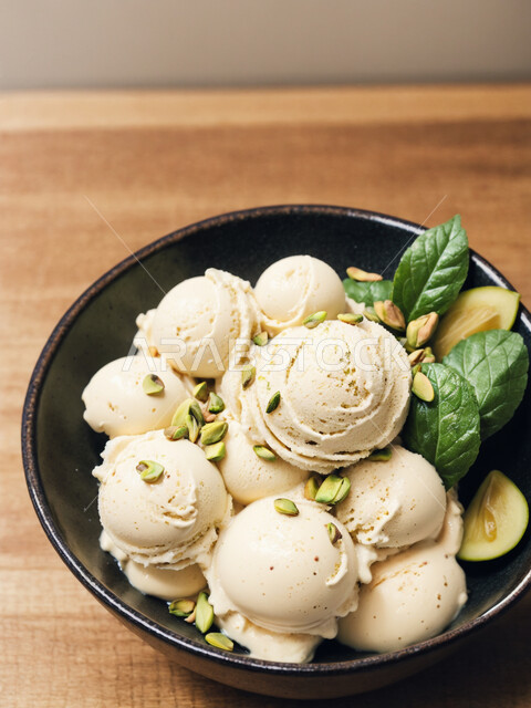A plate of vanilla ice cream balls with pistachios, ice cream with refreshing flavors, artistic methods of serving food, cool summer desserts, high-calorie foods.