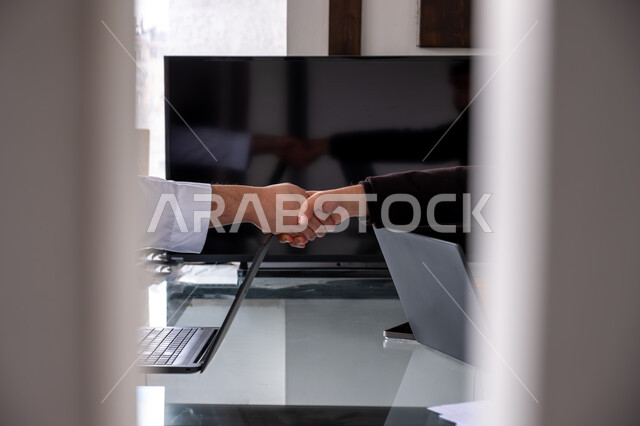 الشراكة والتعاون في إنجاز المهام، شركات ومكاتب في المملكه العربيه السعوديه، عقد اتفاقيات وصفقات جديده, الإتفاق على المشاريع التجارية، صورة مقربة لأيدي رجال أعمال عرب خليجيين سعوديين يقومون بمصافحة بعضهم داخل مقر العمل