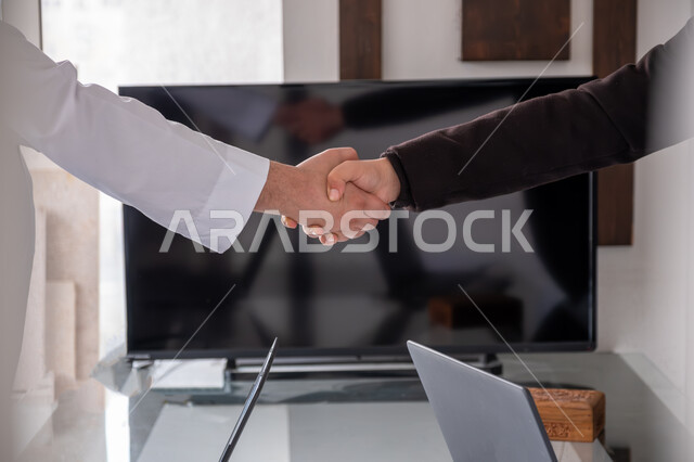 مكاتب وشركات في المملكه العربيه السعوديه، عقد اتفاقيات وصفقات جديده, الإتفاق على المشاريع التجارية، صورة مقربة لأيدي رجال أعمال عرب خليجيين سعوديين يقومون بمصافحة بعضهم داخل مقر العمل، الشراكة والتعاون في إنجاز المهام