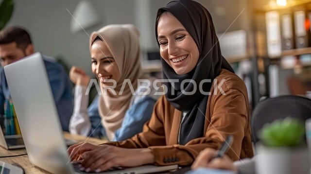 Administrative professions and jobs for women, using modern and advanced technological devices, two veiled Saudi Gulf Arab employees working on the computer inside the company headquarters, companies and offices in the Kingdom of Saudi Arabia, expressions of joy and pleasure while performing work.