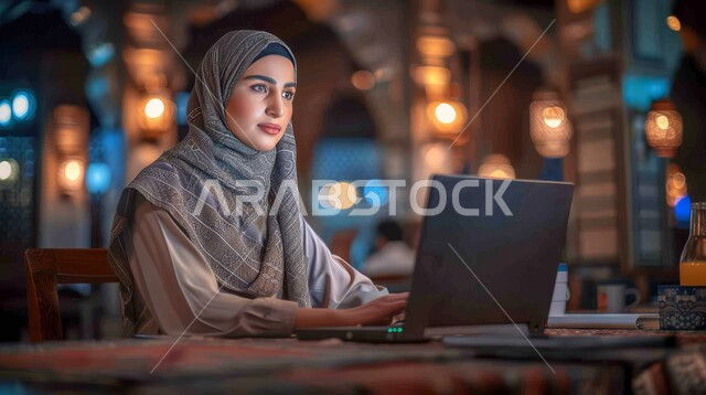 مفهوم إدارة شؤون الأعمال وتنظيمها عبر الاجهزة الحديثة، دمج العمل مع التقنية والتكنولوجيا، صورة مقربة لامرأة عربية خليجية سعودية محجبة تقوم بالعمل على الحاسوب المحمول، مهن ووظائف نسائية سعودية