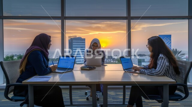 دمج التكنولوجيا والتقنيات لمتابعة وتطوير العمل، سيدات اعمال عربيات خليجيات سعوديات محجبات في اجتماع، استخدام الحاسوب المحمول والأجهزة التقنية الحديثة، مفهوم تحقيق اهداف الشركة، انجاز المهام المكتبية