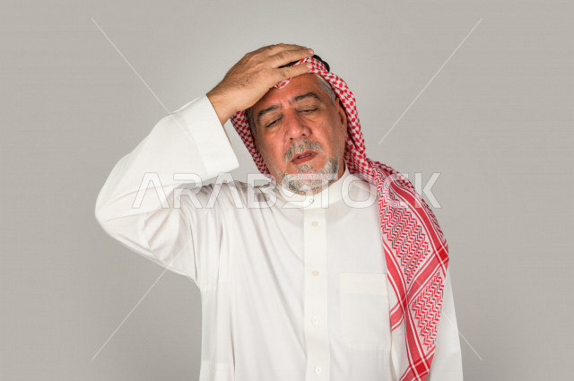 بورتريه لرجل كبير بالسن سعودي خليجي  مريض بإيماءات الوجه و اليدين التي تدل على الألم والمعاناه،  تعابير وجه ، خلفية بيضاء