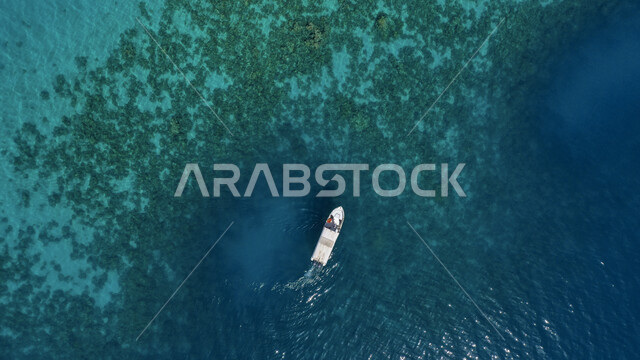 الرحلات الترفيهية والملاحة البحرية، صورة علوية جوية لقارب وسط البحر الأحمر، معالم طبيعية سياحية في المملكة العربية السعودية، المسطحات والثروات المائية في البلاد، منظر المياه الزرقاء النقية