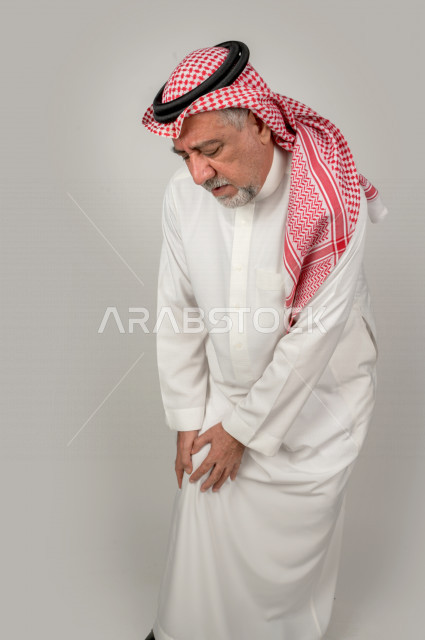 بورتريه لرجل كبير بالسن سعودي خليجي  مريض بإيماءات الوجه و اليدين التي تدل على الألم والمعاناه،  تعابير وجه ، خلفية بيضاء